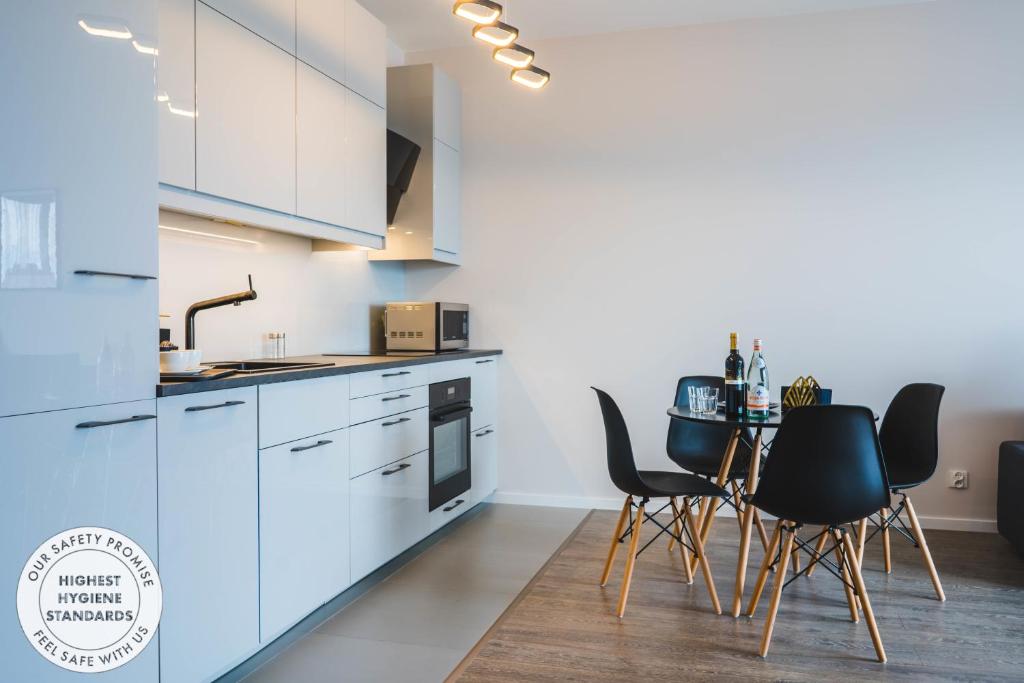 a kitchen with white cabinets and a table with chairs at Blue Raven Downtown Apartments in Gdańsk