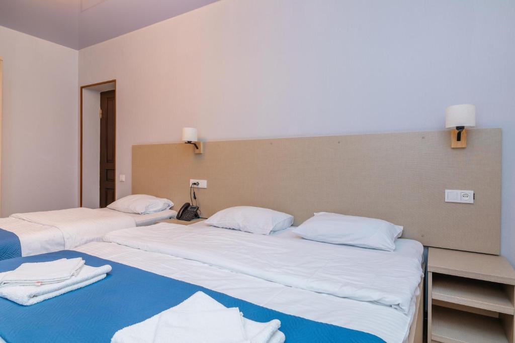 two beds in a room with white sheets at Hotel Green Town in Kutaisi