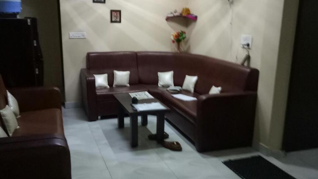 Vamoose Akshat Chindwara في Chhindwāra: غرفة معيشة مع أريكة بنية وطاولة