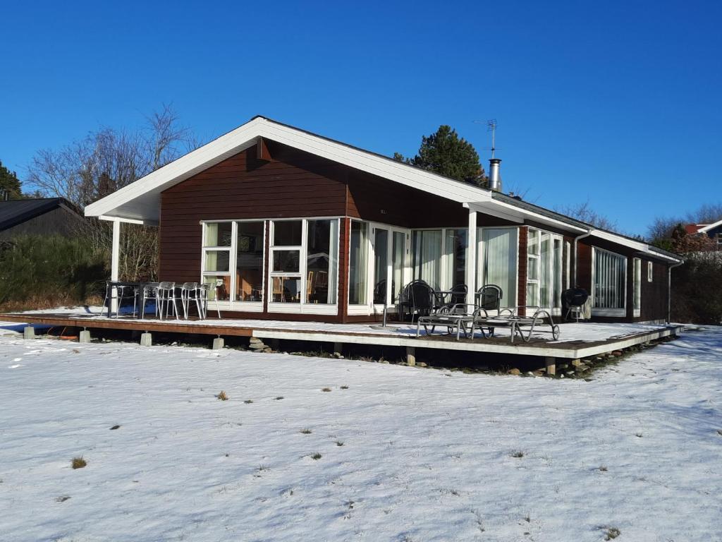 a house with a deck with chairs in the snow at Three-Bedroom Holiday Home in Ebeltoft in Ebeltoft