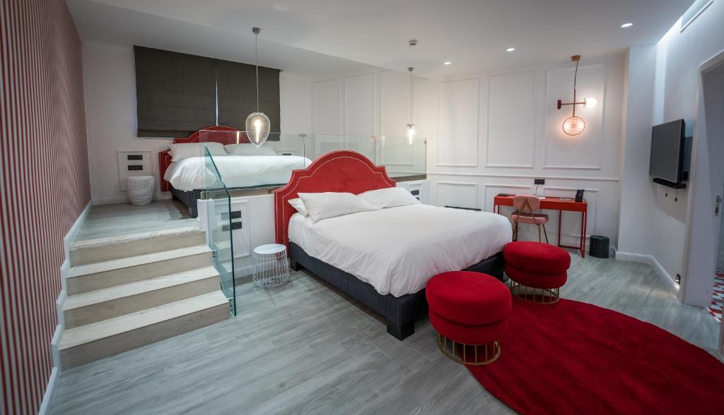 a bedroom with two beds and a red headboard at HOLM Boutique & SPA - IK Collection in St. Julianʼs