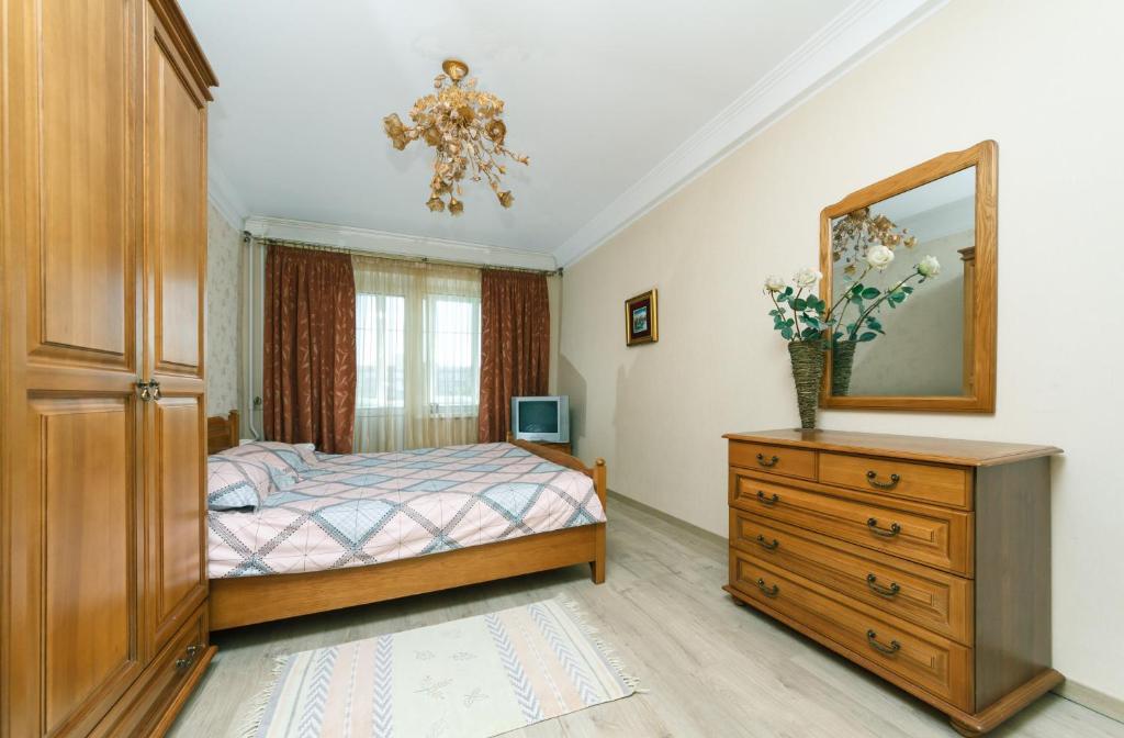 Schlafzimmer mit einem Bett, einer Kommode und einem Spiegel in der Unterkunft Уютная квартира на Лукьяновке in Kiew