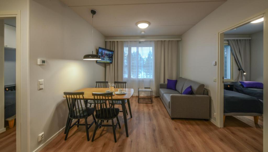 uma sala de estar com uma mesa e cadeiras e um sofá em Vuokatti Sport Apartments em Vuokatti