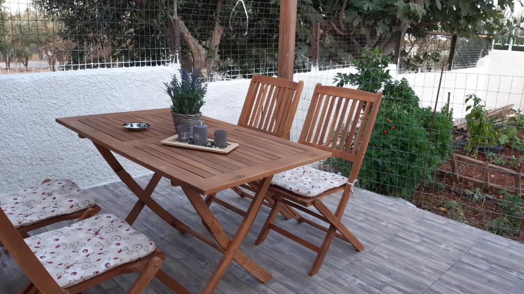 drewniany stół i 2 krzesła na patio w obiekcie Room near the Airport w mieście Pikérmion