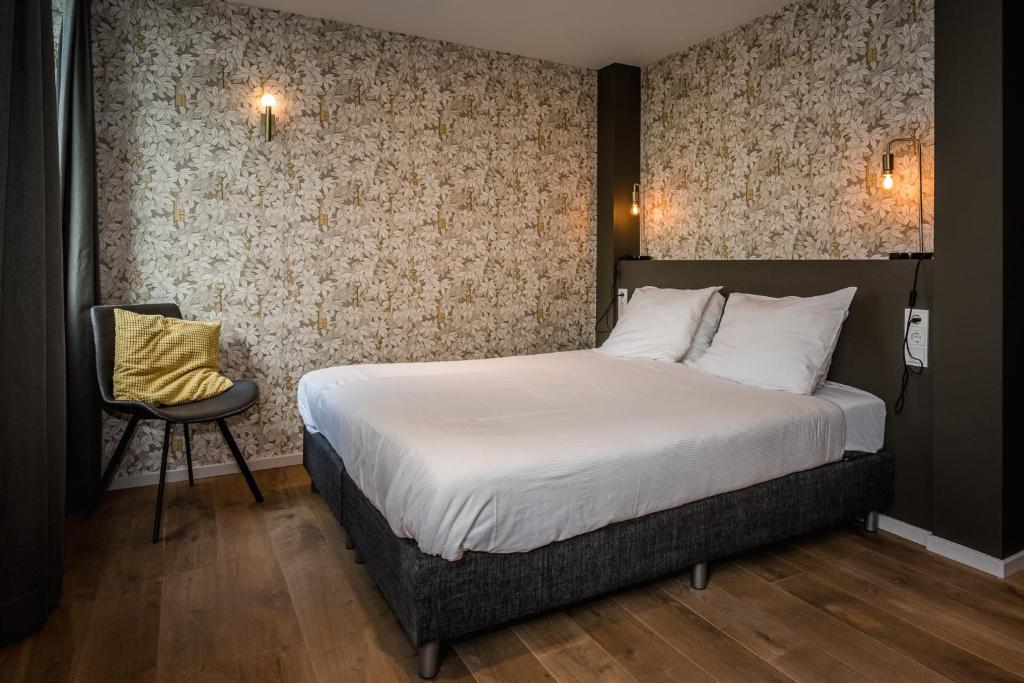 een slaapkamer met een bed en een stoel bij Loods Hotel Vlieland in Oost-Vlieland