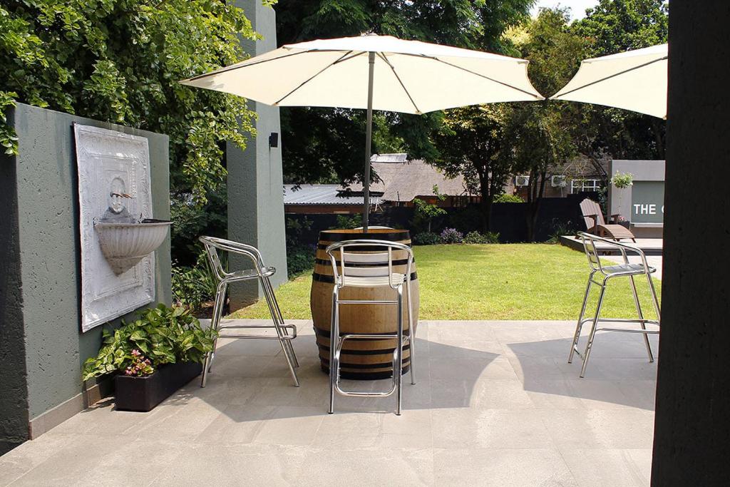 a patio with two chairs and an umbrella at The Guesthouse 6 on Vrede in Johannesburg