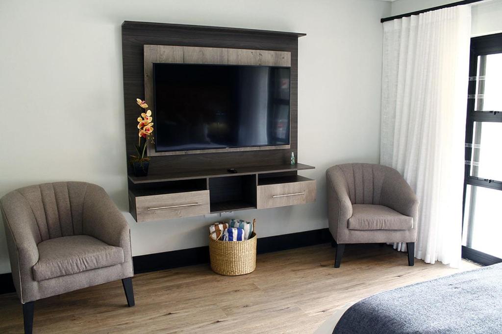 two chairs and a television in a bedroom at The Guesthouse 6 on Vrede in Johannesburg
