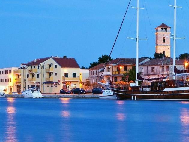 a boat is docked in a harbor with buildings at Apartments Špadina in Tisno
