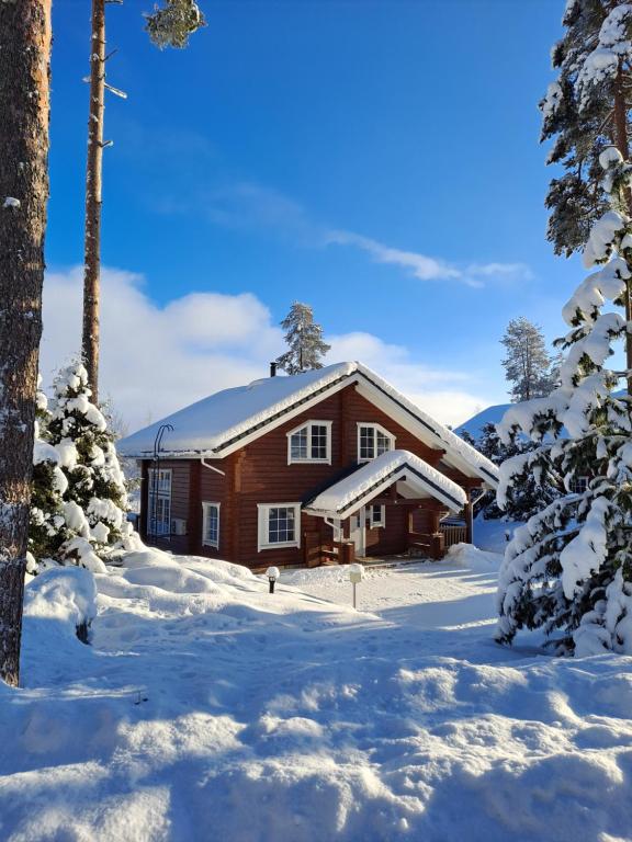 una cabaña de madera en la nieve con árboles nevados en Tahko Hills, en Tahkovuori