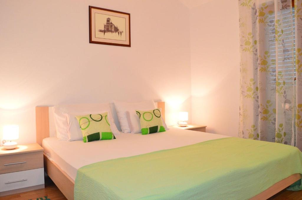 una camera da letto con un grande letto con cuscini verdi di Apartments Vilim Tisno a Tisno (Stretto)