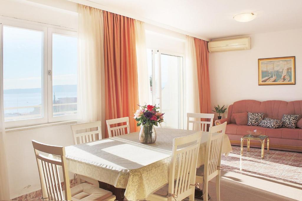 a dining room with a table and chairs and a couch at Apartments Antonio in Baška Voda