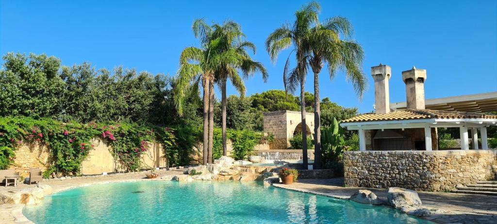 a swimming pool in front of a house with palm trees at Tenuta Moreno in Mesagne