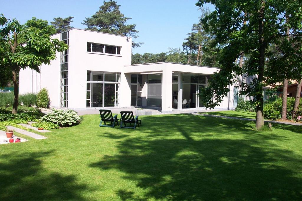 a white house with two chairs in a yard at Nooz - Something Different? in Grobbendonk