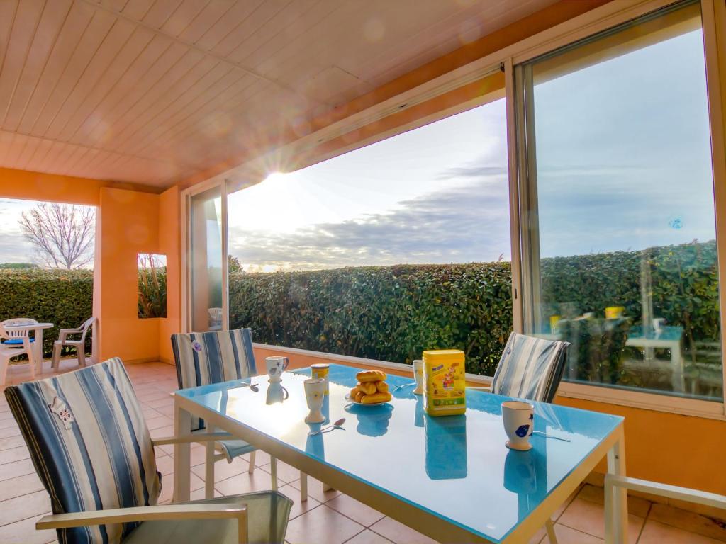 une salle à manger avec une table et des chaises et une grande fenêtre dans l'établissement Apartment Les Rives du Lac-5 by Interhome, au Grau-du-Roi