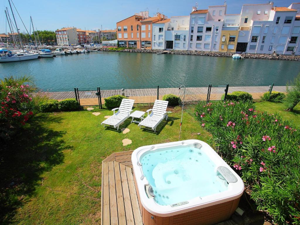 eine Badewanne auf einer Terrasse neben zwei Stühlen in der Unterkunft Holiday Home Île St Martin by Interhome in Cap d'Agde