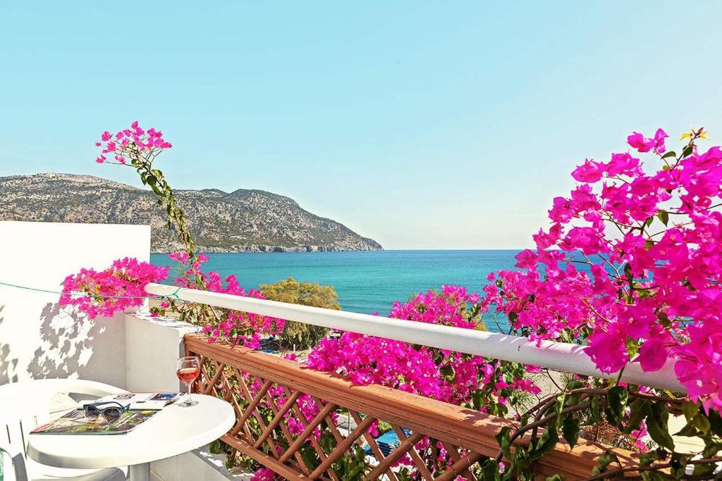 a balcony with pink flowers and a view of the ocean at MINOS BEACH KARPATHoS in Karpathos Town