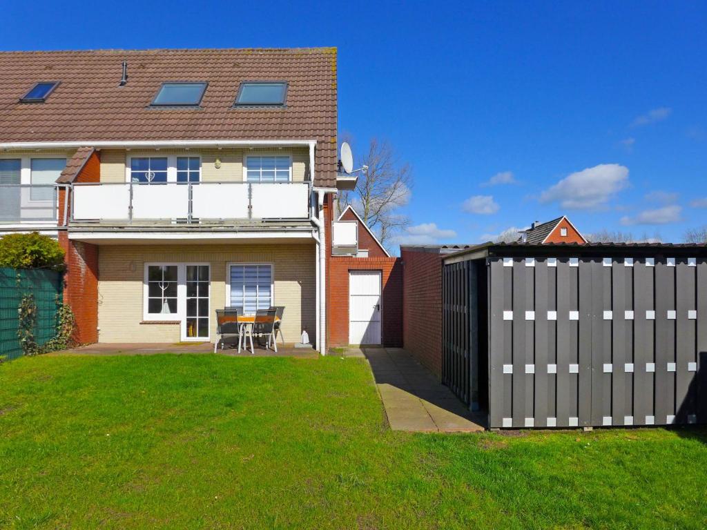 ein Haus mit einem Zaun und einem Tisch im Hof in der Unterkunft Apartment Krabbe by Interhome in Norddeich