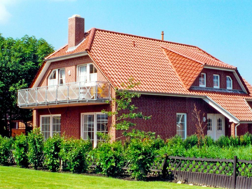 uma casa de tijolos vermelhos com um telhado laranja em Apartment Leuchtturm by Interhome em Norddeich