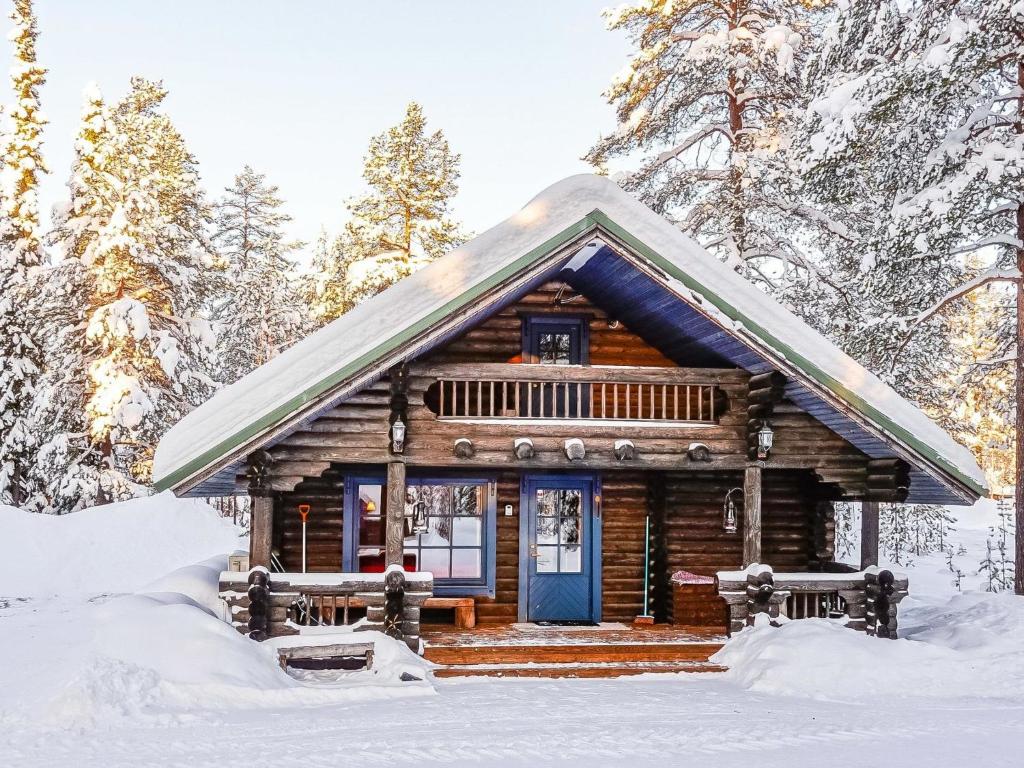 uma cabana de madeira com uma porta azul na neve em Holiday Home Tikkatupa by Interhome em Levi