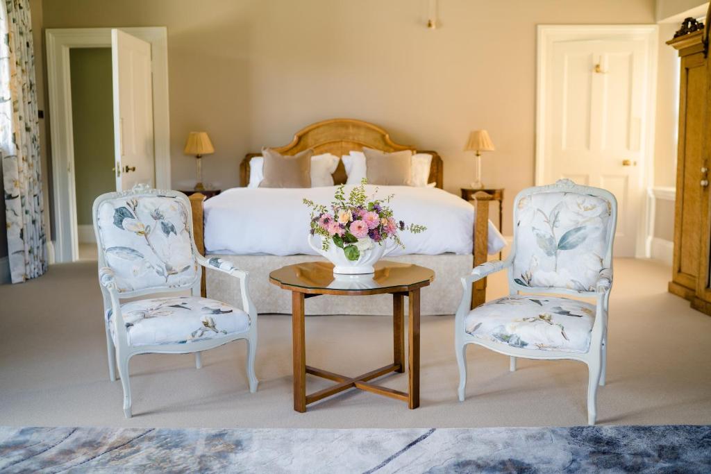 a bedroom with a bed and two chairs and a table with flowers at The South Wing in Salisbury