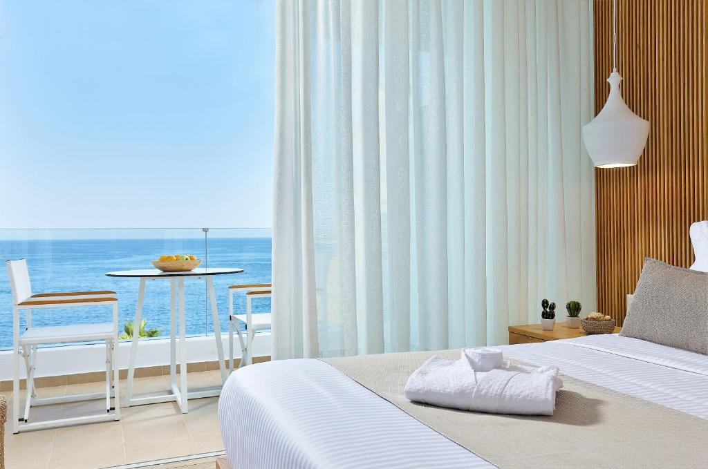 een slaapkamer met een bed en uitzicht op de oceaan bij Citrus Exclusive in Agios Nikolaos
