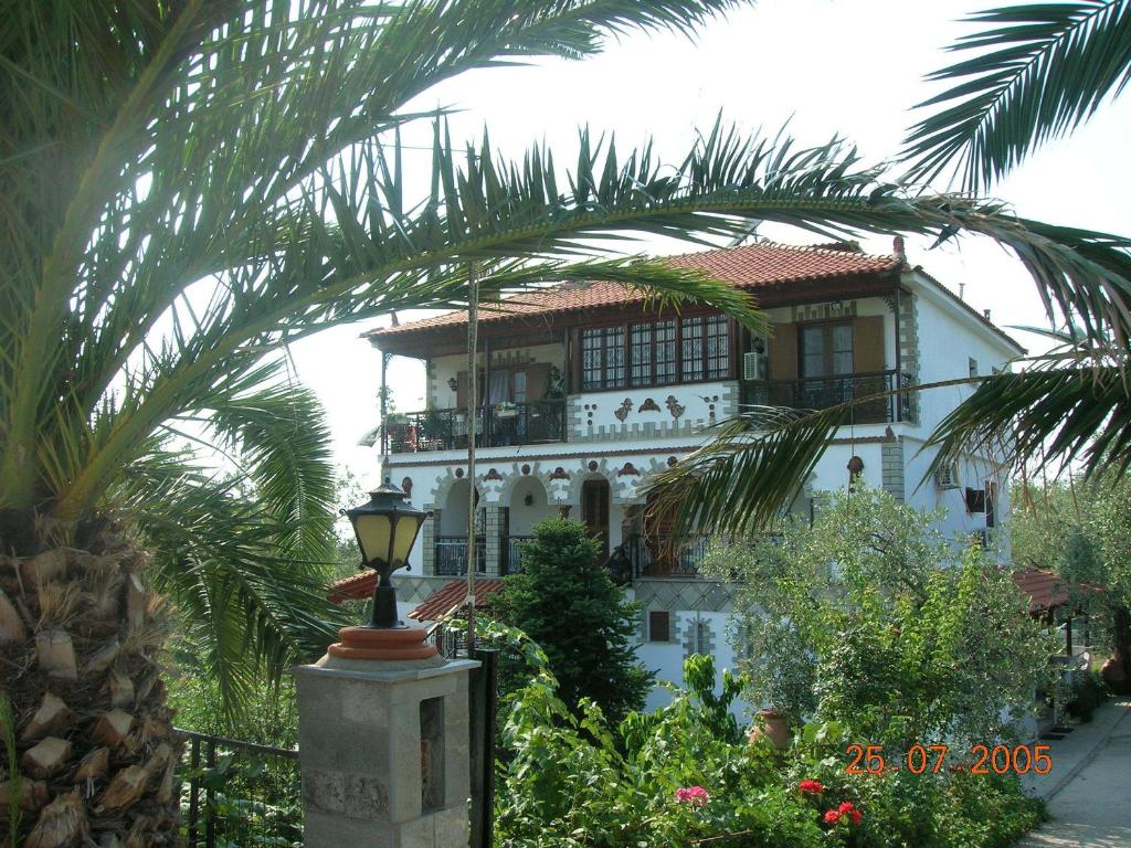 a large white house with a palm tree in front of it at Villa Karapataki in Skala Rachoniou