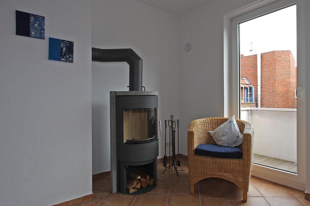 uma sala de estar com uma lareira, uma cadeira e uma televisão em Hellinghaus FeWo 4 Muschelsucher em Wyk auf Föhr