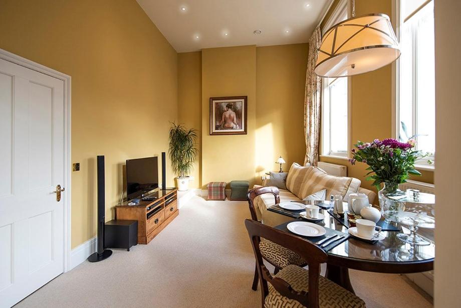 a living room with a table and a couch at Arkle - Five Star Town Centre Apartment, Cheltenham in Cheltenham