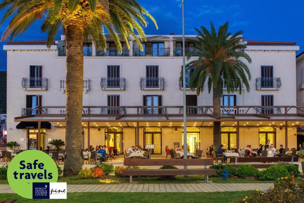 a hotel with palm trees in front of it at Hotel Pine in Tivat