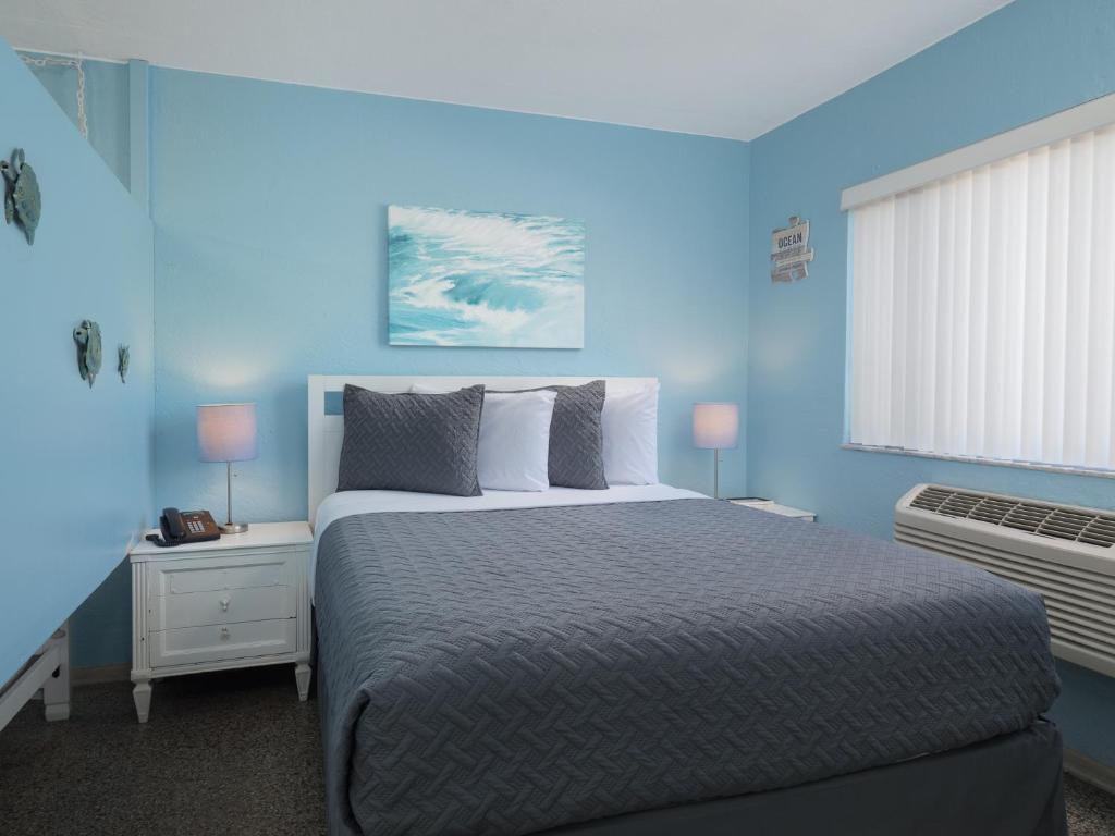 ein blaues Schlafzimmer mit einem großen Bett und einem Fenster in der Unterkunft South Beach Inn - Cocoa Beach in Cocoa Beach