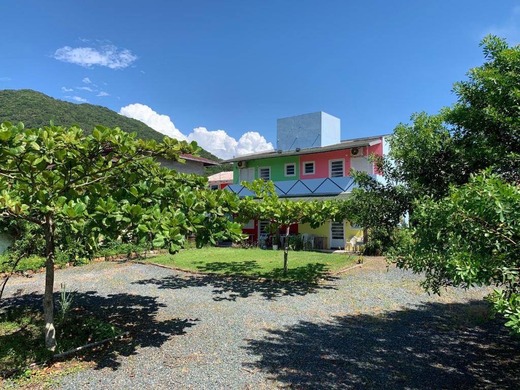 una casa con un patio con árboles delante de ella en AymuraY Hostel e Pousada, en Penha