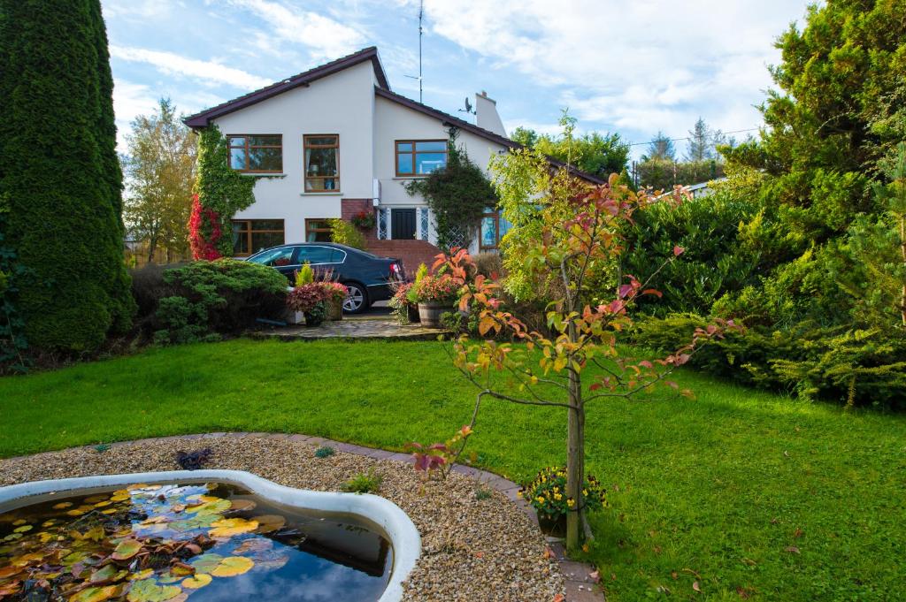 un jardin avec un étang avec un arbre et une maison dans l'établissement Aisleigh Guest House, à Carrick-on-Shannon