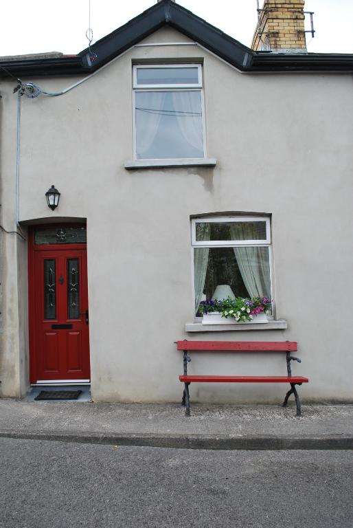um banco vermelho em frente a uma casa branca com uma janela em 5 Ellesmere Avenue em Bundoran