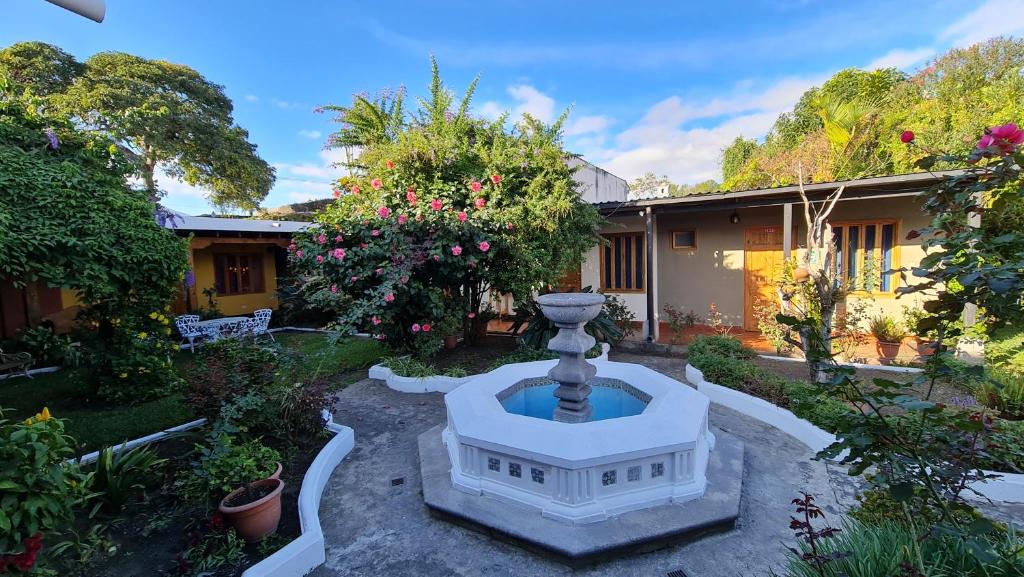 un jardín con una fuente frente a una casa en Hotel San Jorge by Porta Hotels, en Antigua Guatemala