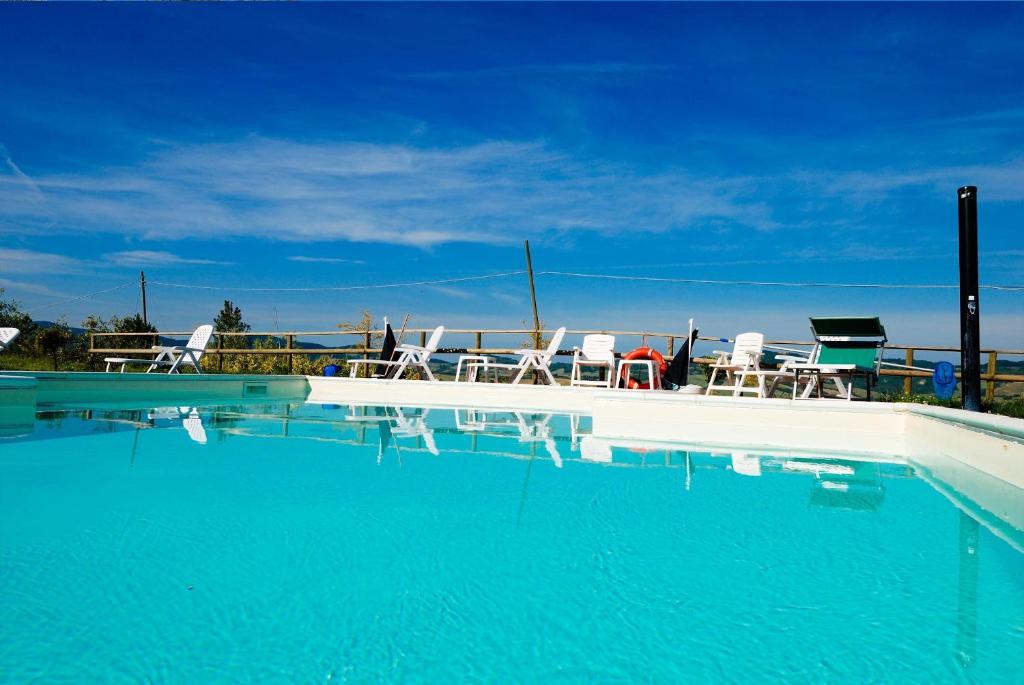 a swimming pool with chairs and blue water at Agriturismo Il Canterino in Guardistallo