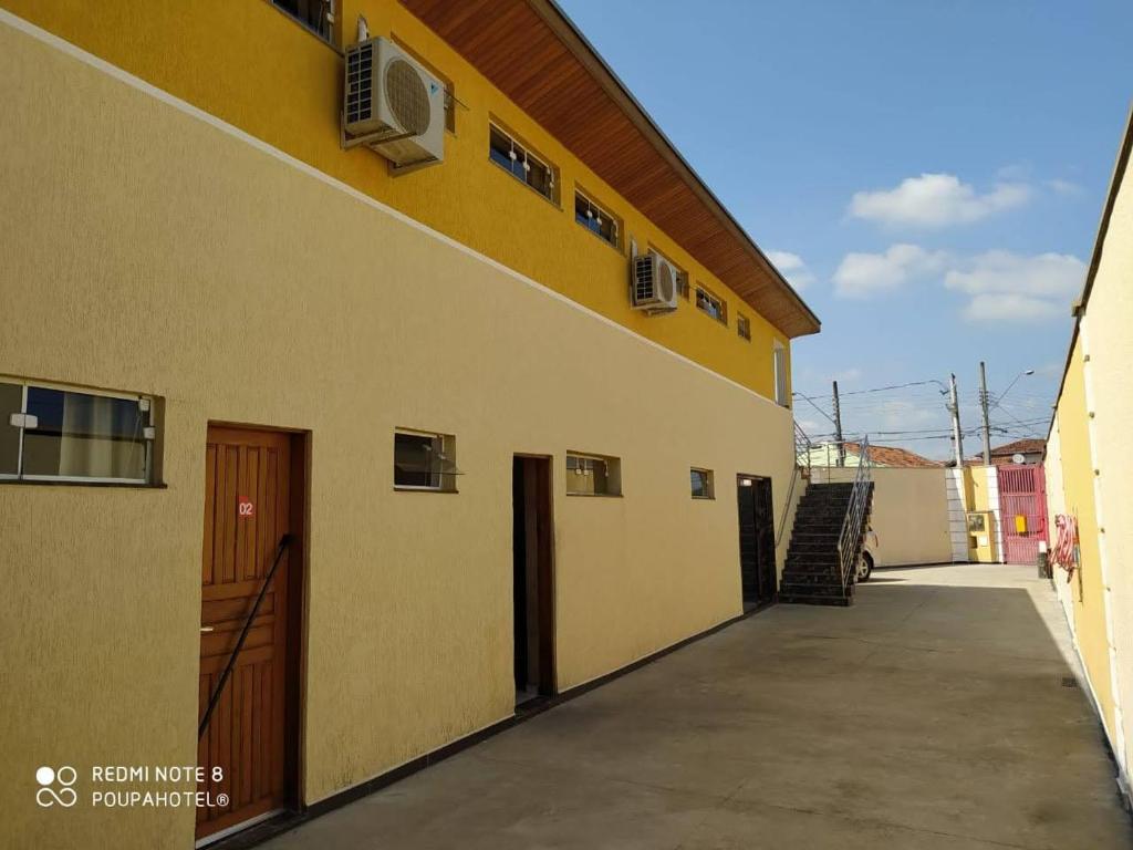 a yellow building with a door and a hallway at Poupahotel Unidade Bairro in Taubaté