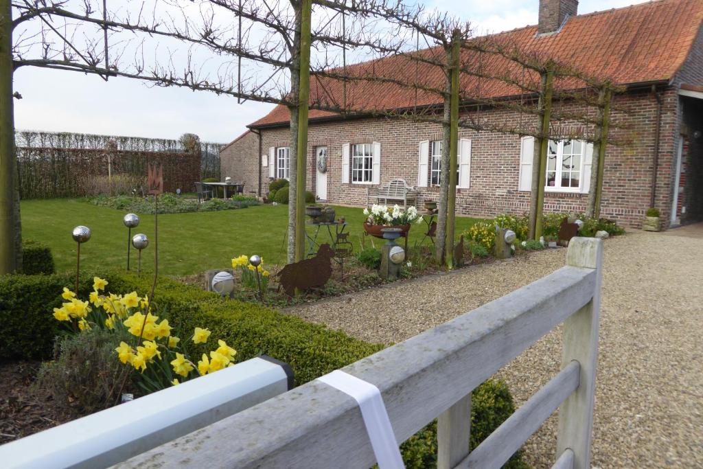 une maison avec une clôture blanche en face d'un jardin dans l'établissement Vakantiewoning Jérôme, à Heuvelland