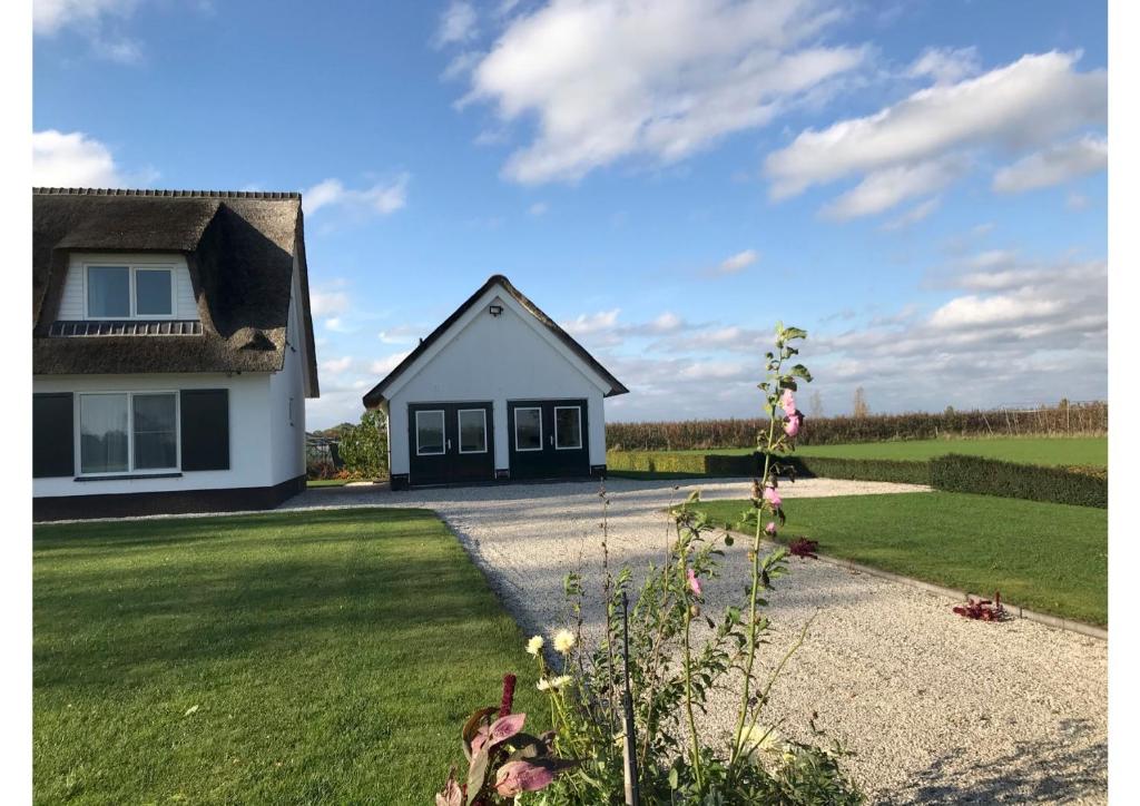 een klein wit huis met een grasveld bij B&B De Spiegel - Genieten van rust en ruimte in Cothen