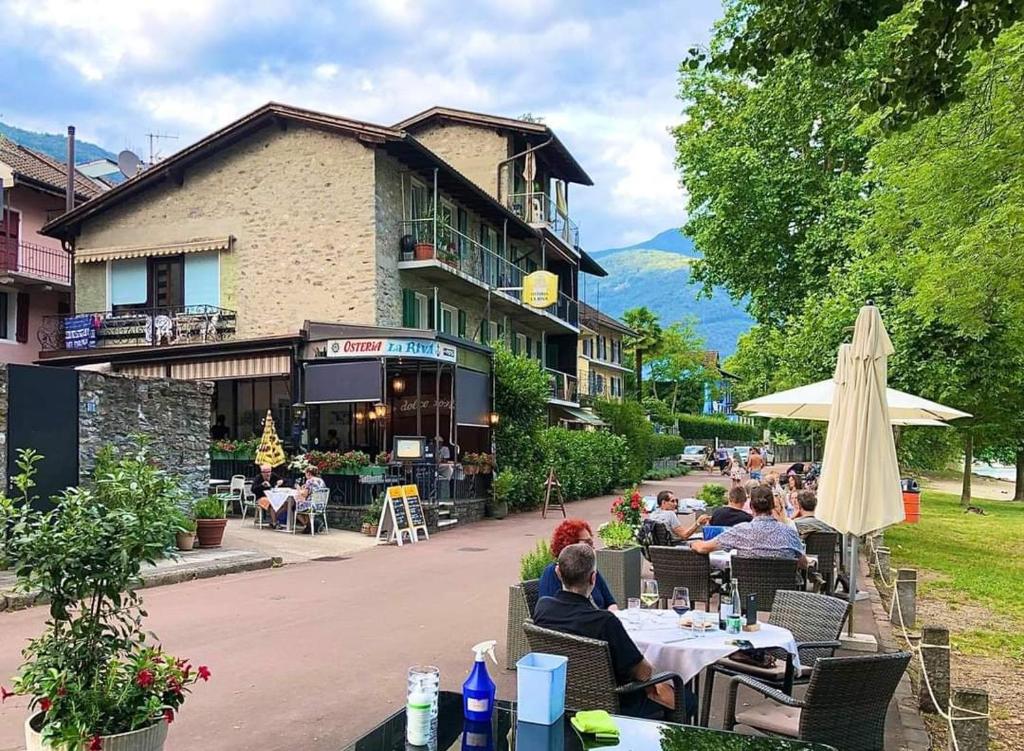 eine Gruppe von Personen, die vor einem Gebäude an Tischen sitzen in der Unterkunft Osteria La Riva in Locarno