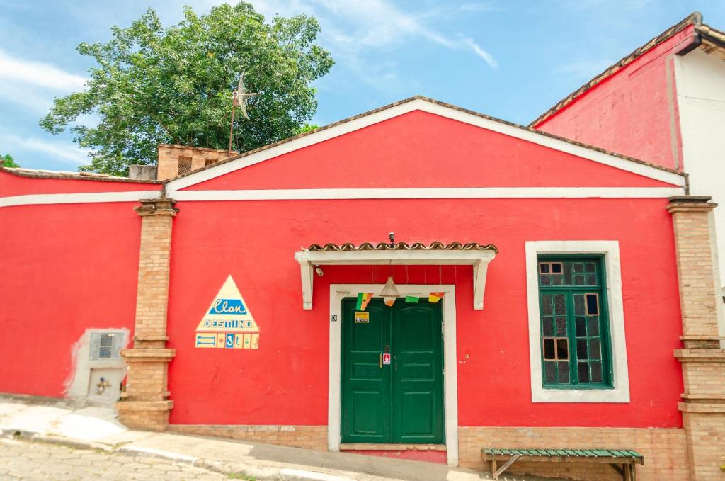 czerwony budynek z zielonymi drzwiami w obiekcie Clan.Destino Hostel w mieście Ilhabela