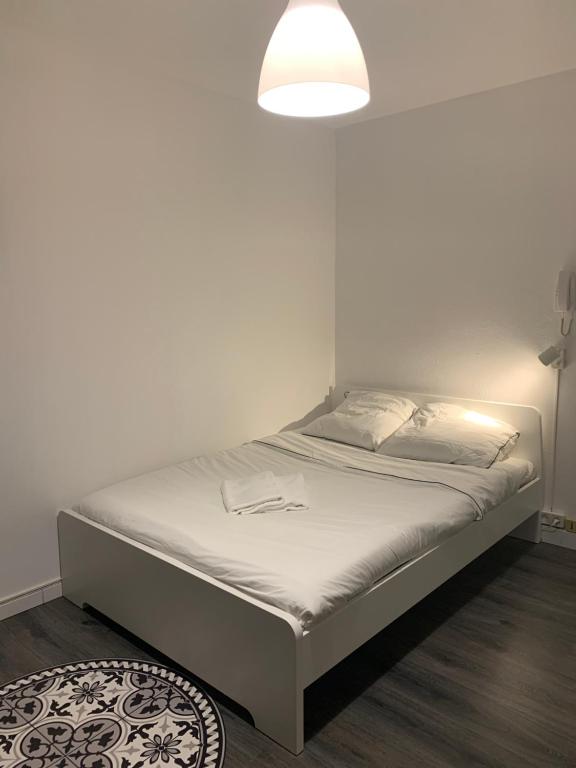 een bed in een kamer met een witte muur bij La Rose in Straatsburg