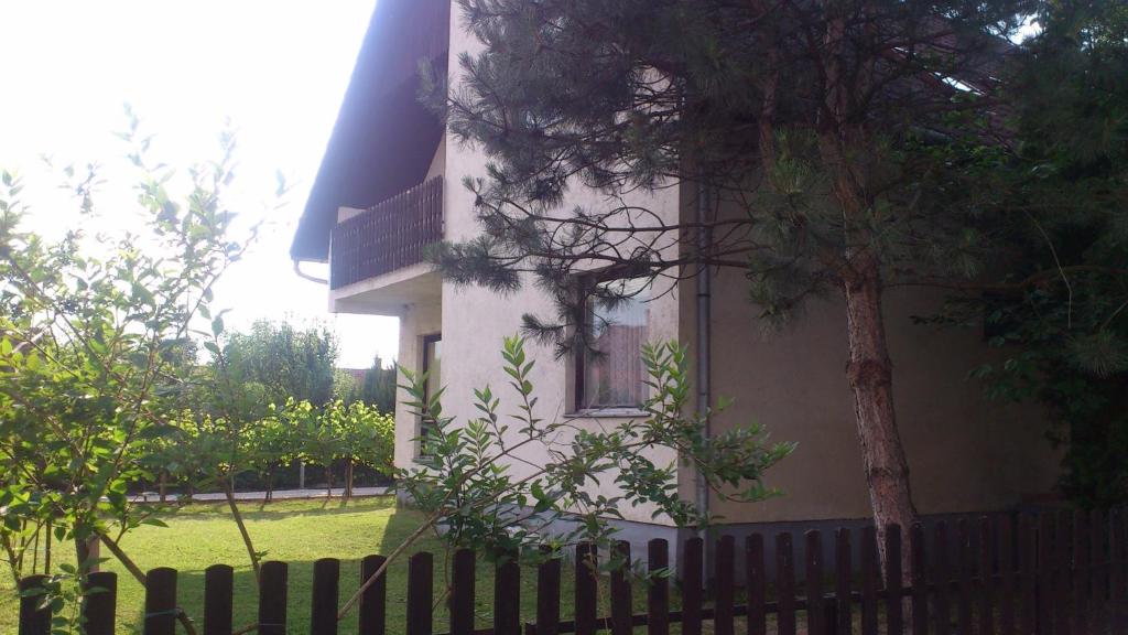 バラトンフェニヴェシュにあるHoliday home in Balatonfenyves 18430の塀の横に木のある白い建物