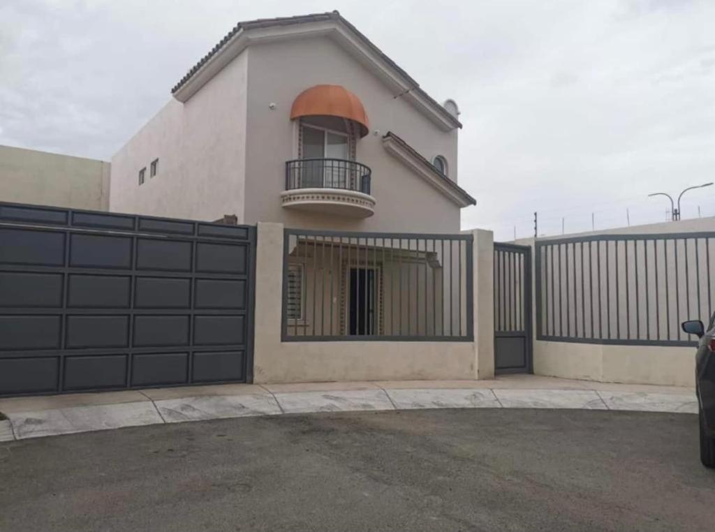 une maison blanche avec un portail et une clôture dans l'établissement CASA PONIENTE, à Hermosillo