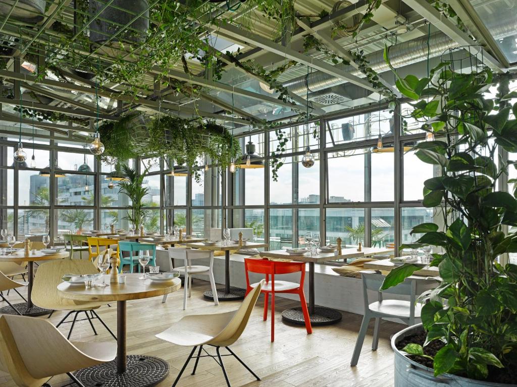 a restaurant with tables and chairs and plants at 25hours Hotel Bikini Berlin in Berlin