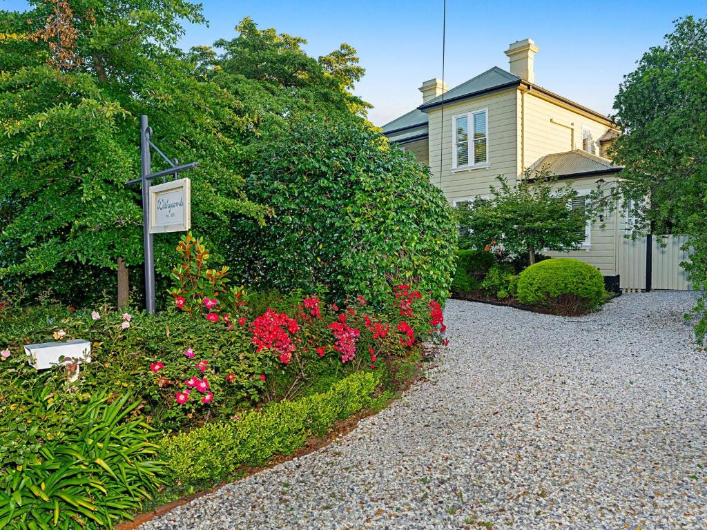 une maison avec un panneau dans un jardin fleuri dans l'établissement Withycombe, Bowral, à Bowral