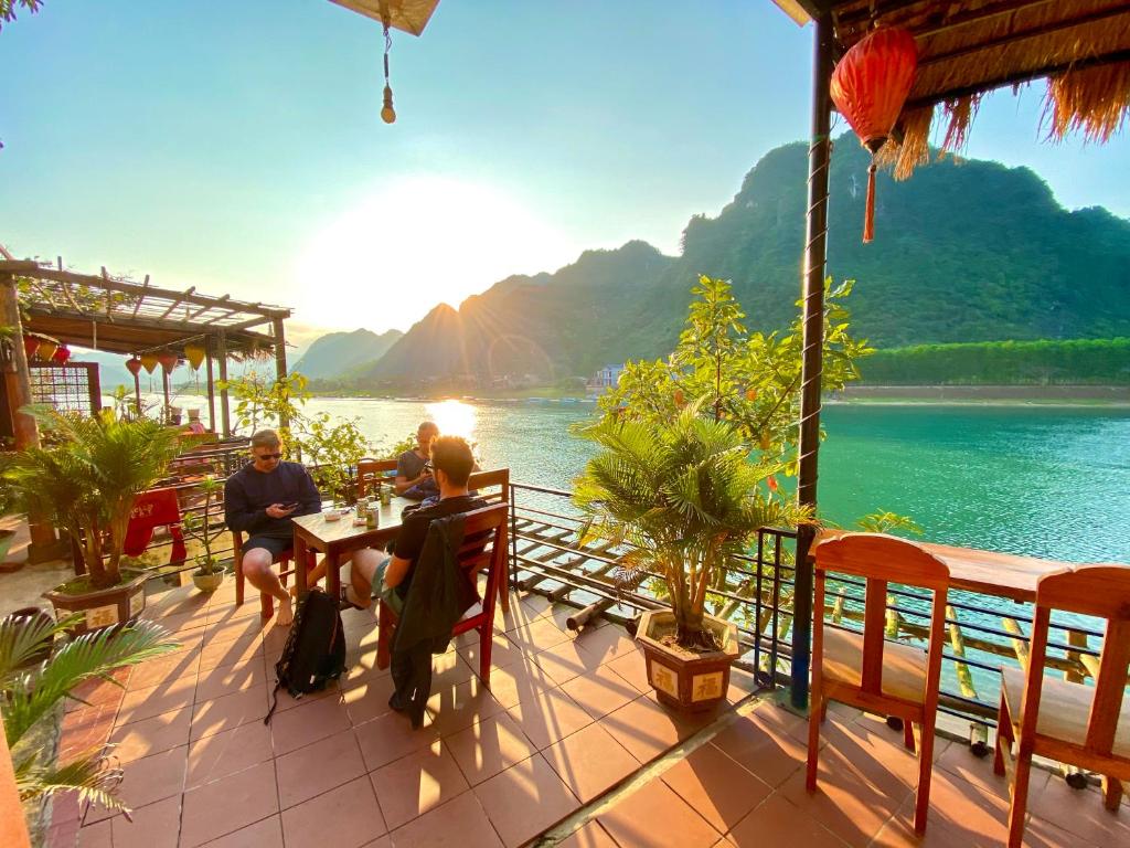 un gruppo di persone seduti a un tavolo vicino all'acqua di Phong Nha Coco Riverside a Phong Nha