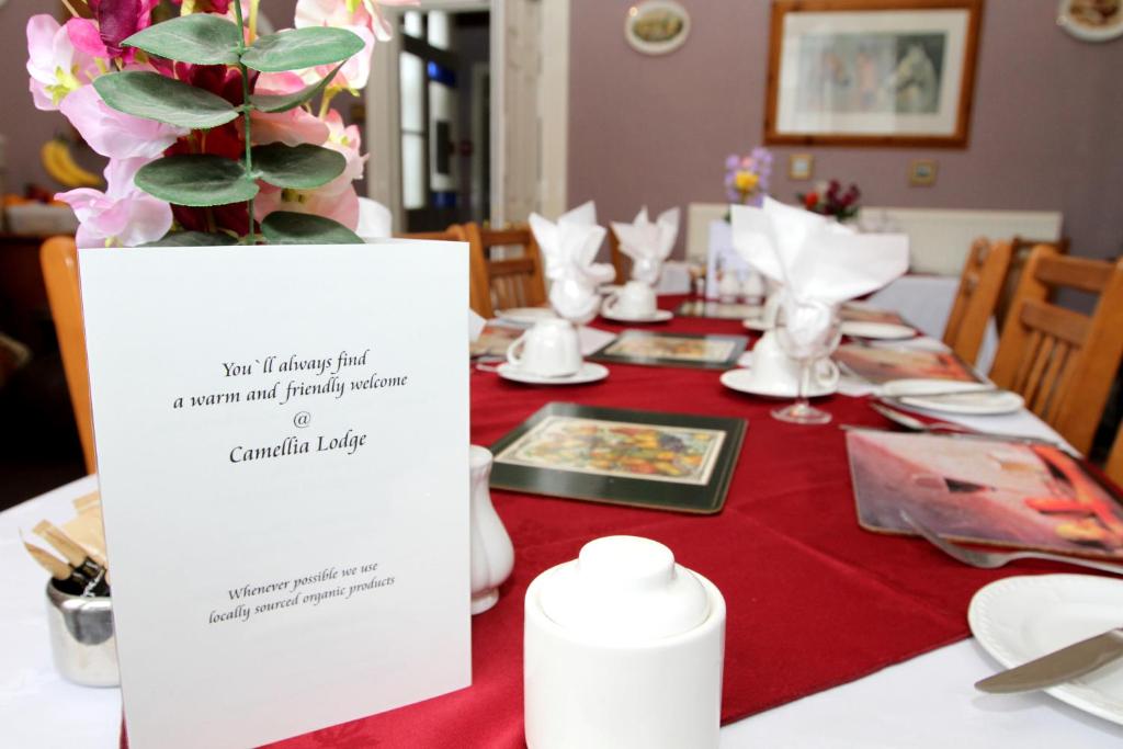 a table with a red table cloth and a sign on it at Camellia Lodge Guest House in Weston-super-Mare