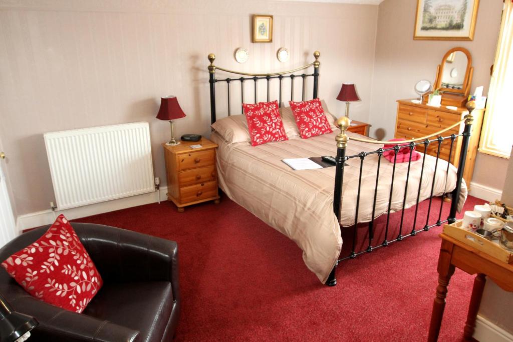 a bedroom with a bed with red pillows and a chair at Camellia Lodge Guest House in Weston-super-Mare