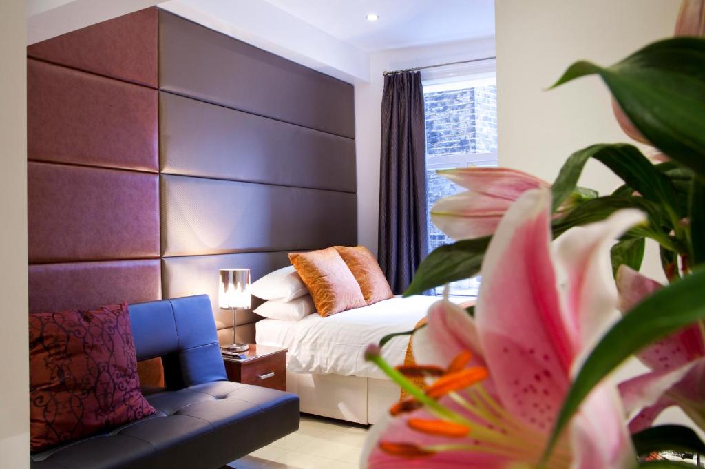 a bedroom with a bed and a couch and a flower at City Inn Russell Square in London