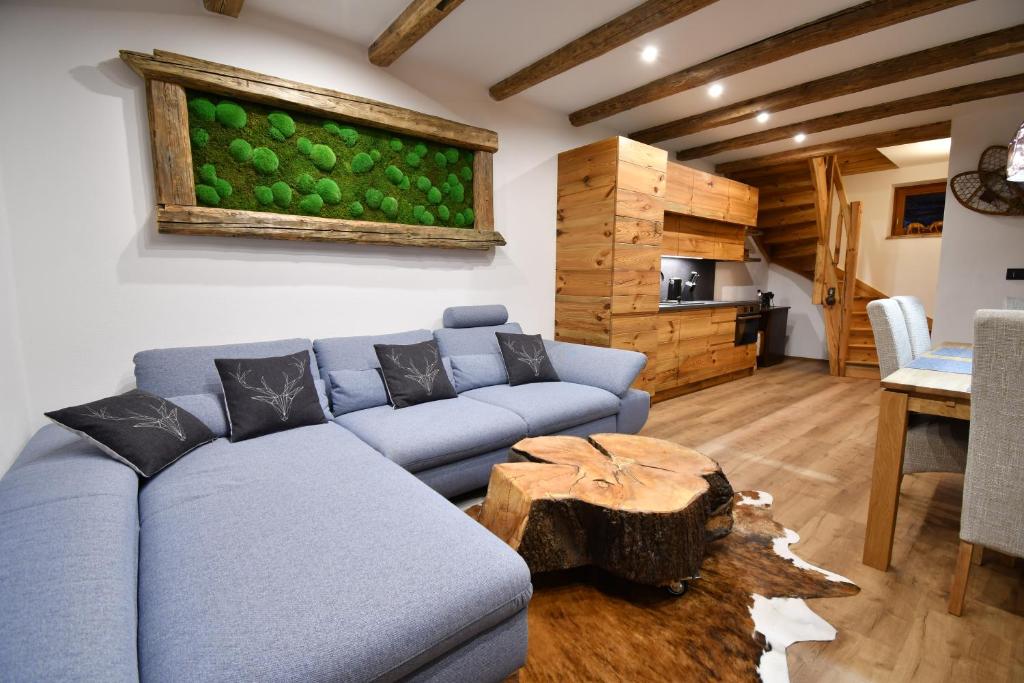 a living room with a blue couch and a table at Chalet Apartments Maštal in Železná Ruda